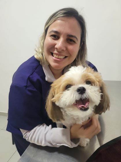 Dra. Andressa segurando um cachorro durante atendimento domiciliar